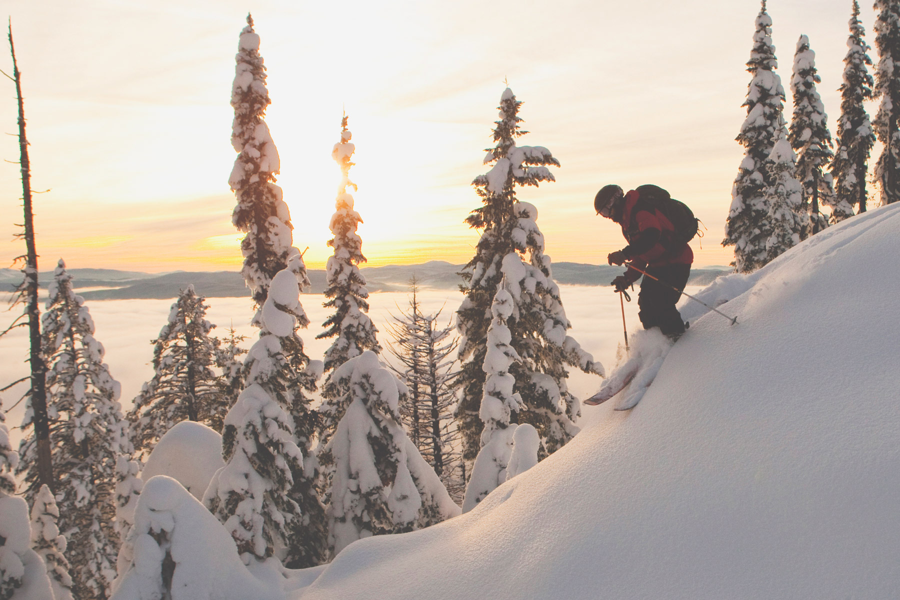 Skier descending tall powder-capped snow peak in GNPG resort