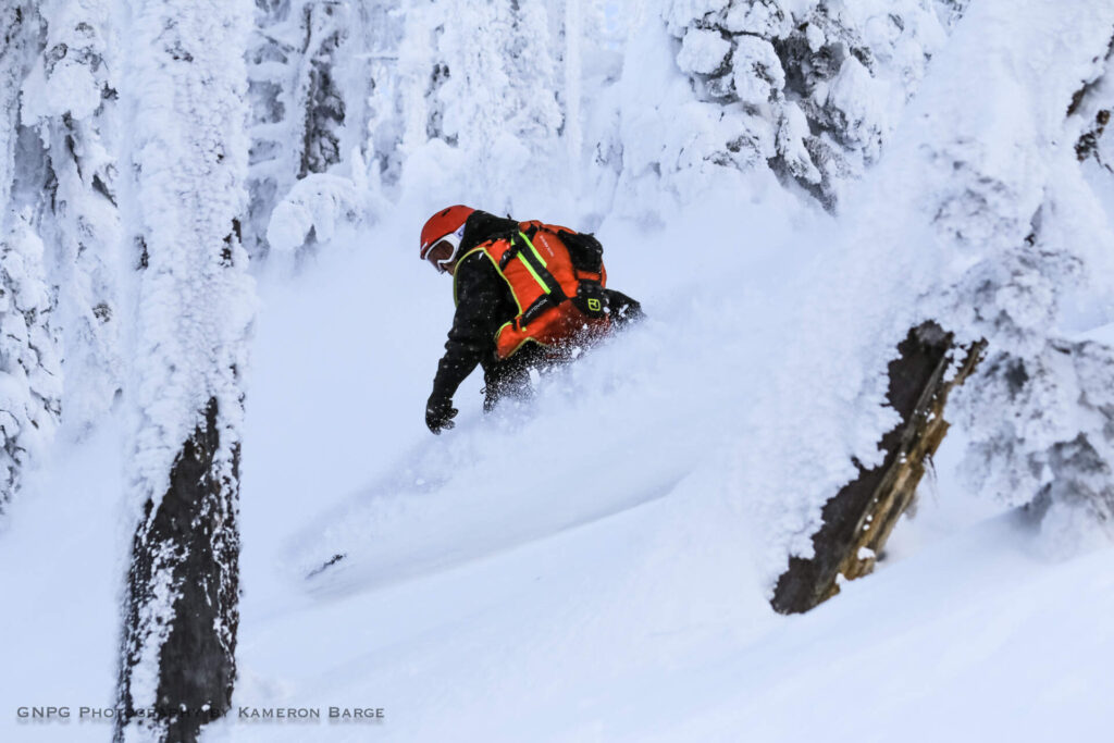 Snowboarder riding untouched snow during a cat skiing trip with GNPG.