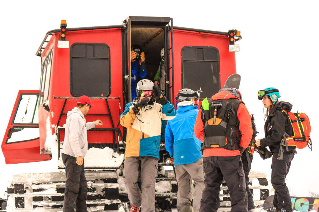 Skiers gearing up beside GNPG snowcat before loading for a powder day.