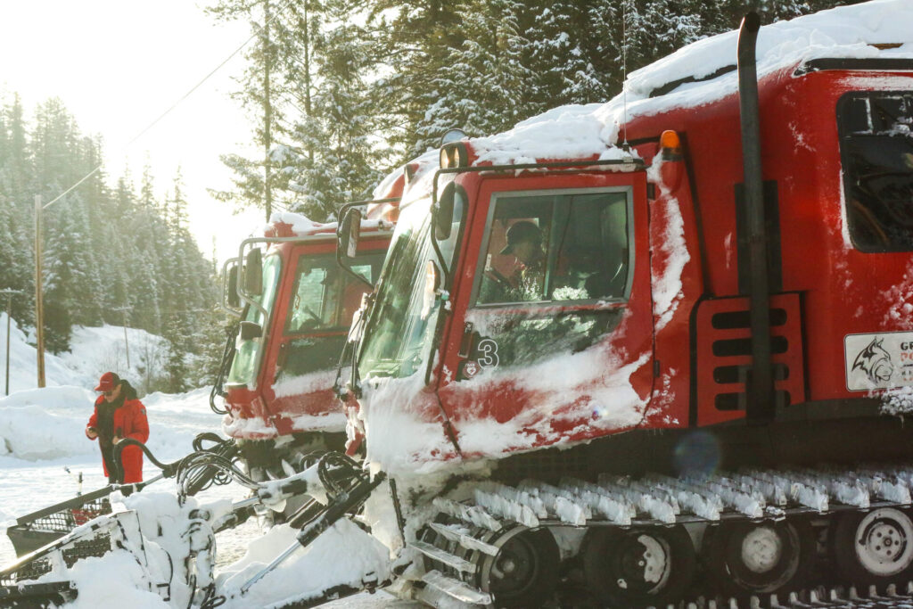 Snowcats parked in fresh powder, ready to take guests on backcountry runs.