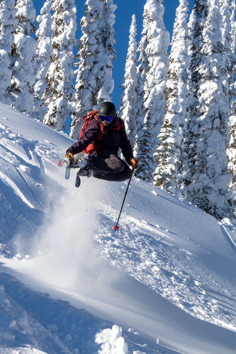 Skier making an air jump as they carve through fresh powder at GNPG
