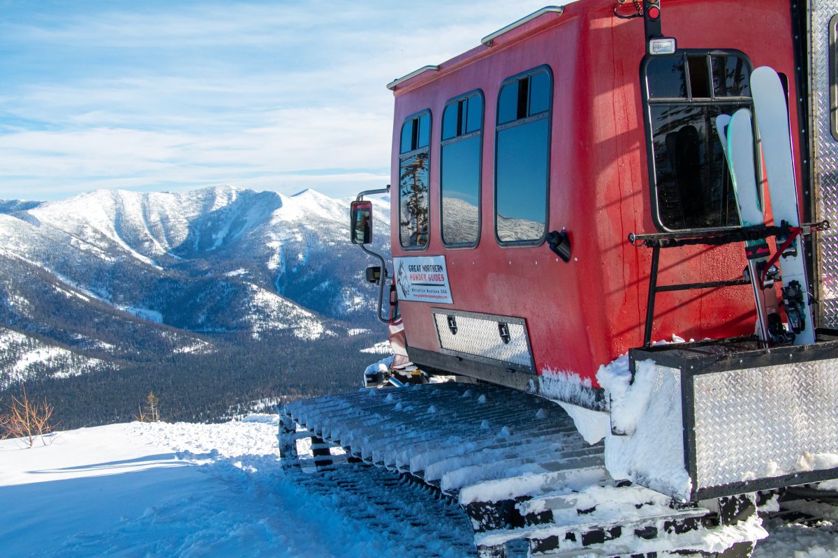Close-up of Great Northern Powder Guides cat ski with Montana's snow-capped Northern Rockies in background
