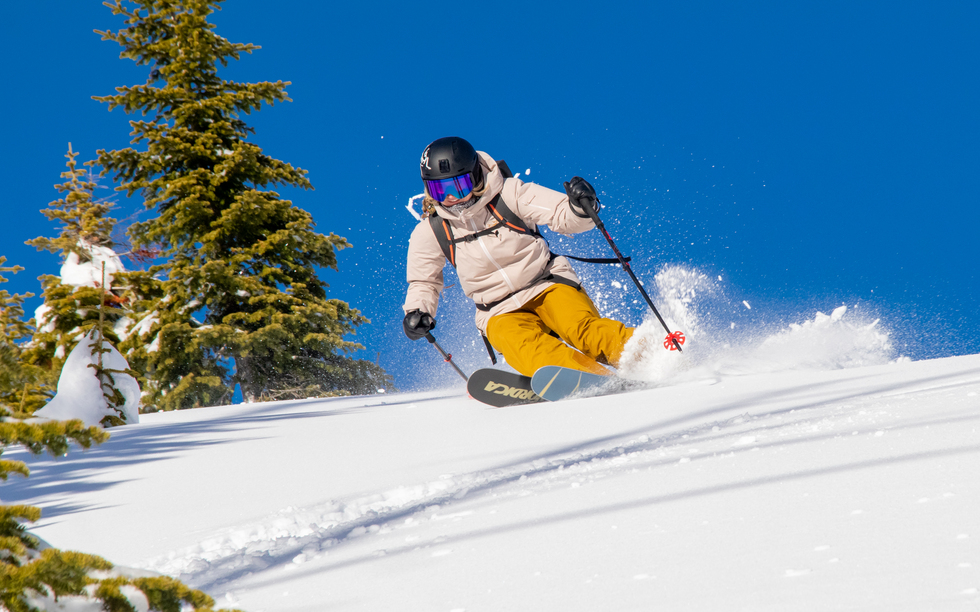 Advanced skier carving turns while descending untouched backcountry terrain.