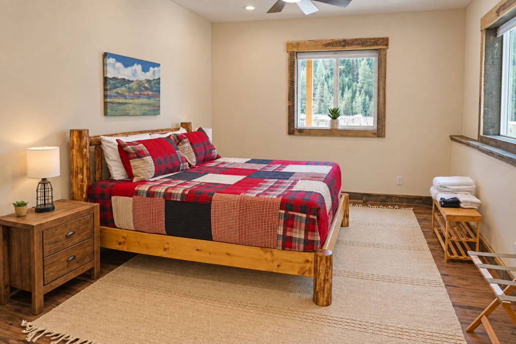 Bedroom inside the log cabin at Bar W Ranch with handcrafted log bed and red plaid bedding