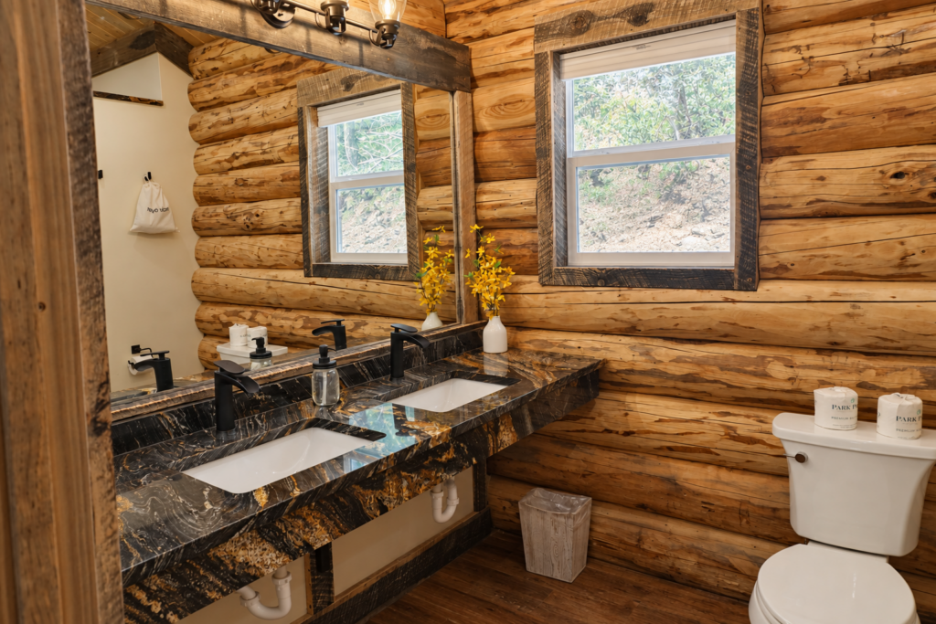 Bathroom inside the log cabin at Bar W Ranch with double vanity, stone countertop, and log walls